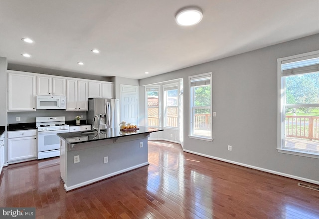 kitchen with white appliances, white cabinetry, a kitchen island with sink, and sink