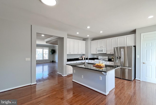 kitchen featuring white cabinets, white appliances, a kitchen island with sink, and sink