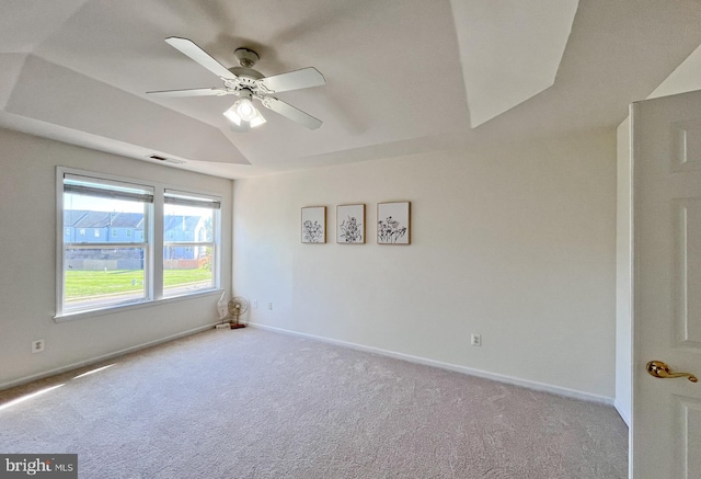 carpeted spare room featuring ceiling fan, a raised ceiling, and lofted ceiling