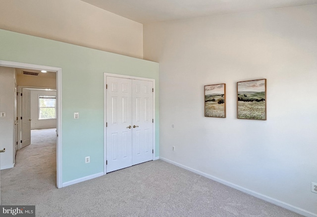 unfurnished bedroom featuring light carpet and a closet