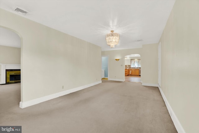 unfurnished room featuring a chandelier and light colored carpet