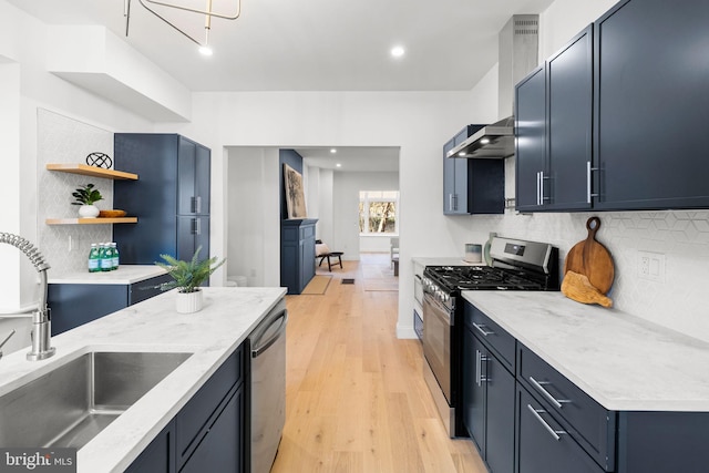 kitchen with backsplash, wall chimney range hood, sink, light hardwood / wood-style flooring, and appliances with stainless steel finishes