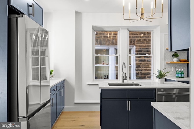 bar with pendant lighting, sink, appliances with stainless steel finishes, a notable chandelier, and light stone counters