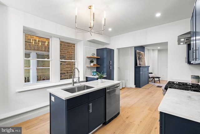 kitchen with appliances with stainless steel finishes, light wood-type flooring, sink, a center island with sink, and a chandelier