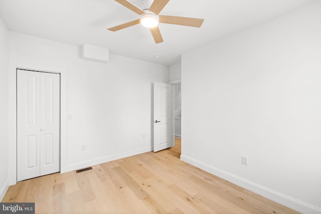 unfurnished bedroom featuring ceiling fan, a closet, and light wood-type flooring