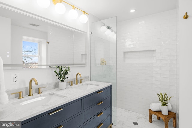 bathroom featuring a tile shower, tile patterned flooring, and vanity