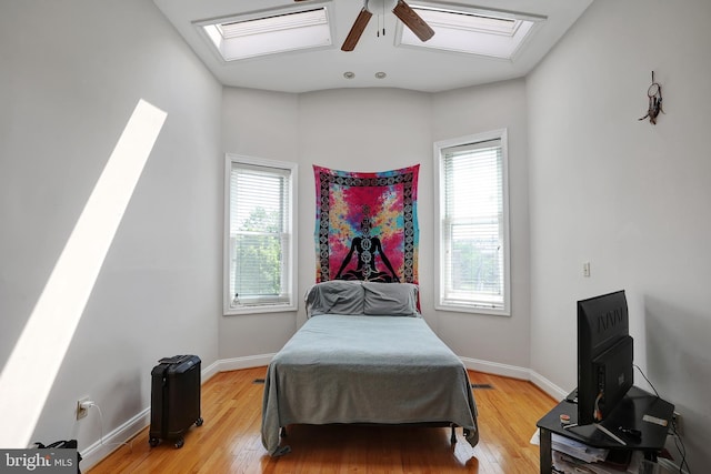 bedroom with a skylight, ceiling fan, and hardwood / wood-style floors