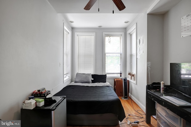 bedroom with ceiling fan, light wood-type flooring, and multiple windows