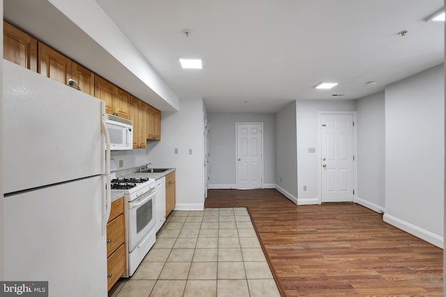 kitchen featuring sink, light hardwood / wood-style floors, and white appliances