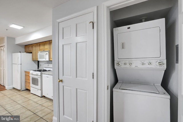 washroom featuring stacked washer and dryer and light tile patterned floors