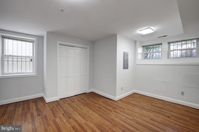 unfurnished bedroom featuring hardwood / wood-style flooring, electric panel, and a closet