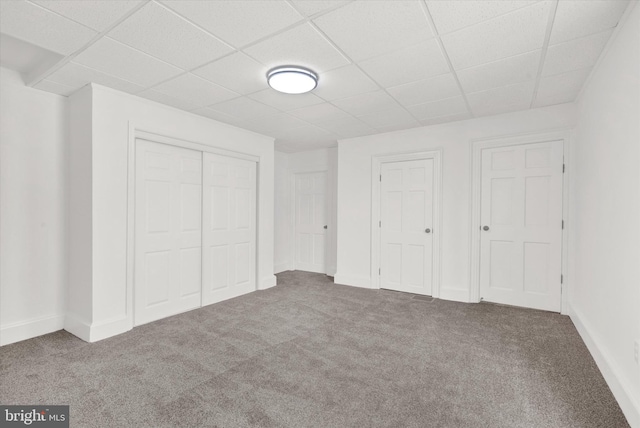 unfurnished bedroom featuring a drop ceiling and carpet floors