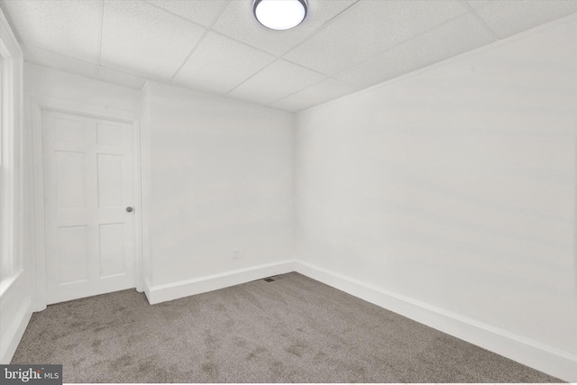 carpeted empty room with a paneled ceiling