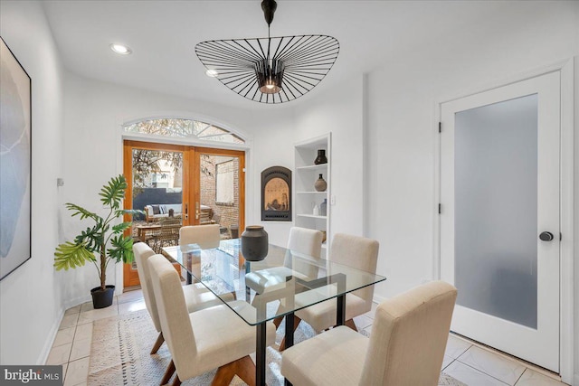 tiled dining space featuring built in features and french doors