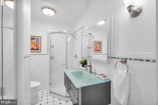 bathroom featuring an enclosed shower, vanity, toilet, and tile walls