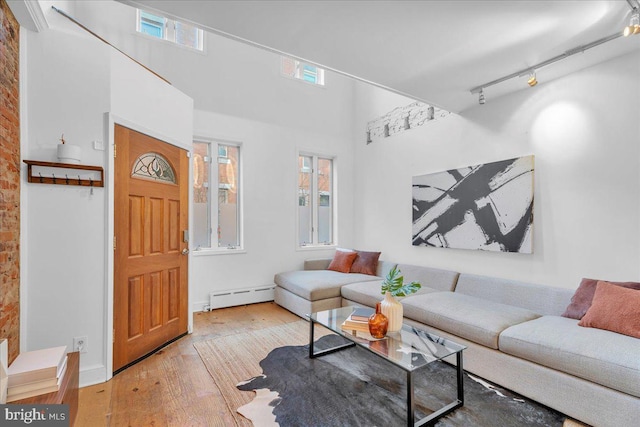 living room with light wood-type flooring, rail lighting, and baseboard heating