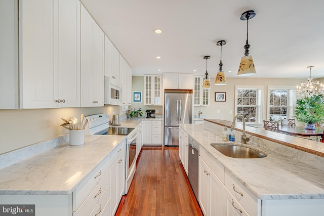 kitchen with a spacious island, appliances with stainless steel finishes, white cabinets, and decorative light fixtures