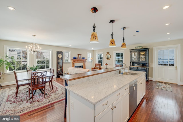 kitchen featuring stainless steel dishwasher, sink, a center island with sink, and white cabinets