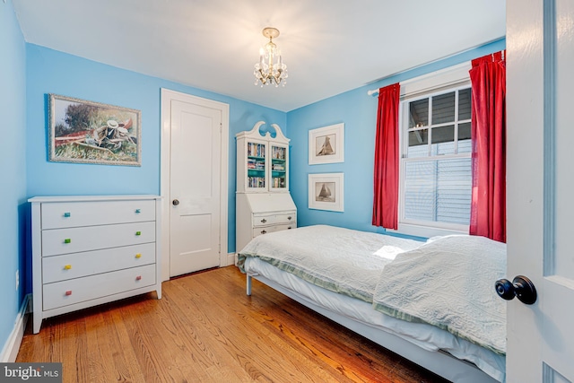 bedroom featuring an inviting chandelier and light hardwood / wood-style flooring