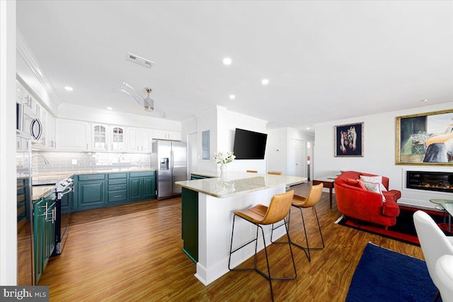 kitchen with white cabinets, backsplash, light hardwood / wood-style floors, a kitchen island, and appliances with stainless steel finishes