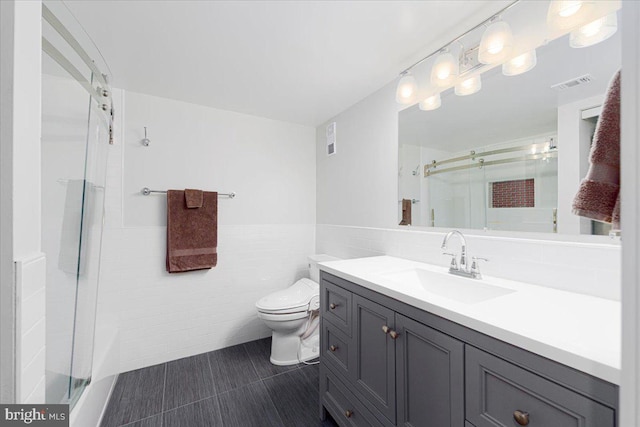 bathroom featuring vanity, tile patterned flooring, toilet, tile walls, and an enclosed shower