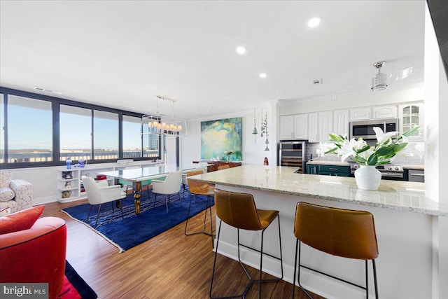 kitchen with pendant lighting, white cabinetry, a kitchen breakfast bar, and wood-type flooring