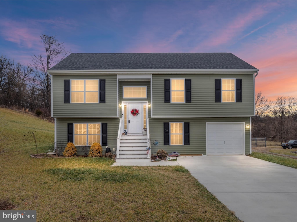 split foyer home featuring a garage and a lawn