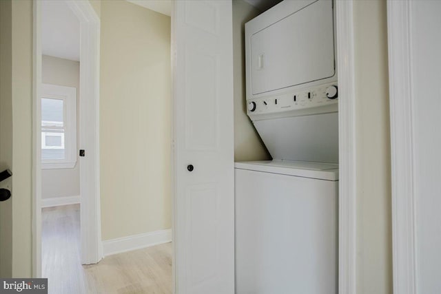 laundry room featuring light wood-type flooring and stacked washing maching and dryer