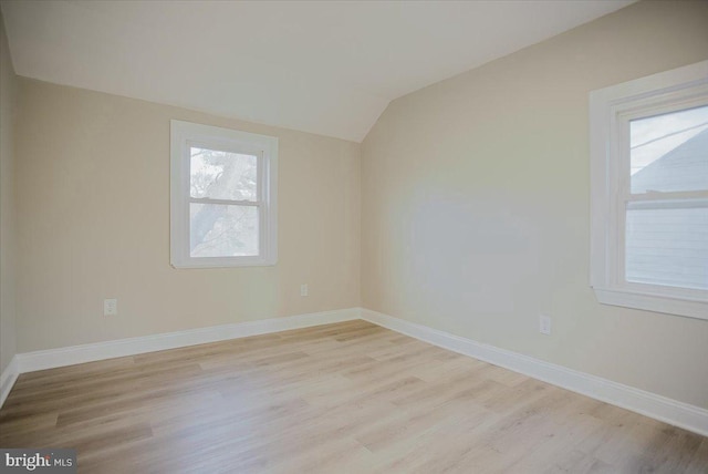 unfurnished room with light wood-type flooring and vaulted ceiling