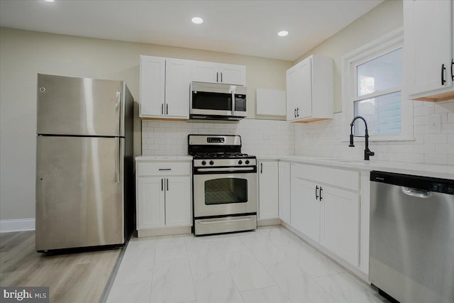 kitchen with white cabinets, decorative backsplash, sink, and stainless steel appliances