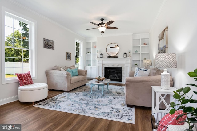 living room with crown molding, dark hardwood / wood-style floors, ceiling fan, and built in shelves