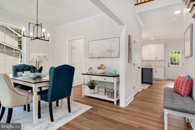 dining space with an inviting chandelier, ornamental molding, and hardwood / wood-style flooring