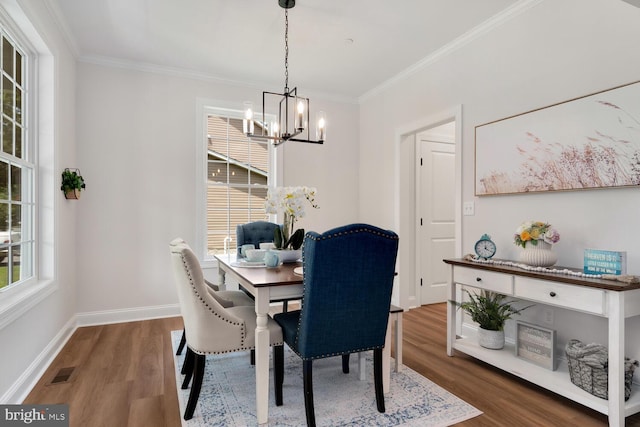 dining room featuring an inviting chandelier, ornamental molding, plenty of natural light, and dark hardwood / wood-style flooring