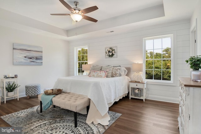 bedroom featuring dark wood-type flooring, ceiling fan, and a tray ceiling