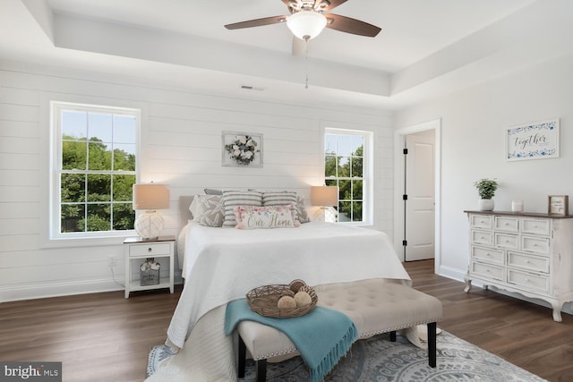 bedroom featuring dark wood-type flooring, ceiling fan, and a tray ceiling