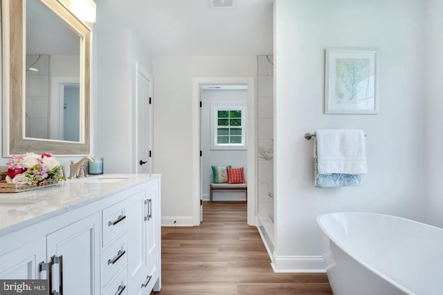 bathroom with a tub to relax in, hardwood / wood-style floors, and vanity