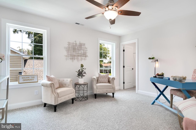 living area featuring light carpet, a wealth of natural light, and ceiling fan