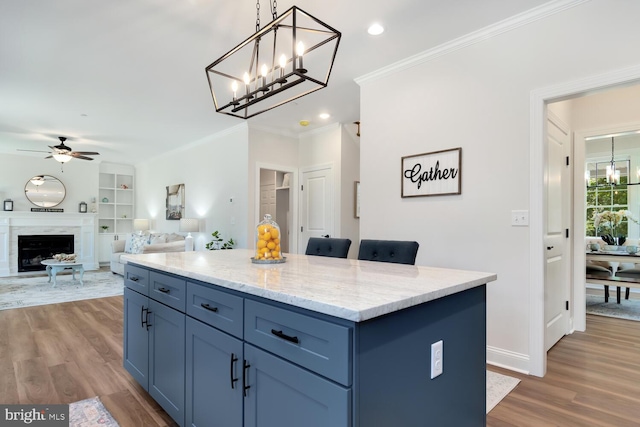 kitchen featuring ceiling fan, hanging light fixtures, wood-type flooring, a kitchen island, and built in shelves