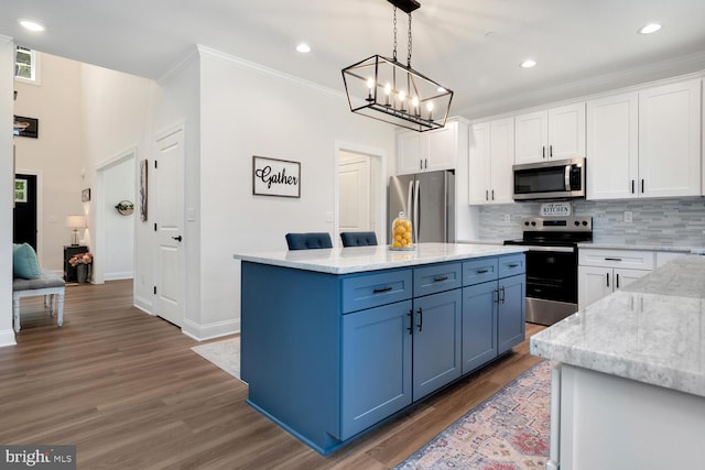 kitchen featuring appliances with stainless steel finishes, a kitchen island, pendant lighting, decorative backsplash, and white cabinets