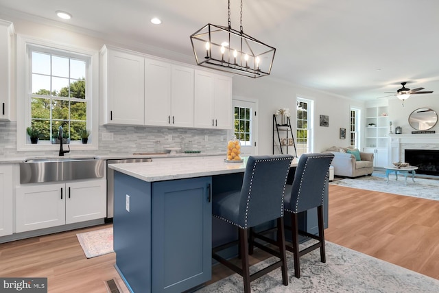 kitchen featuring sink, crown molding, hanging light fixtures, white cabinets, and a kitchen island