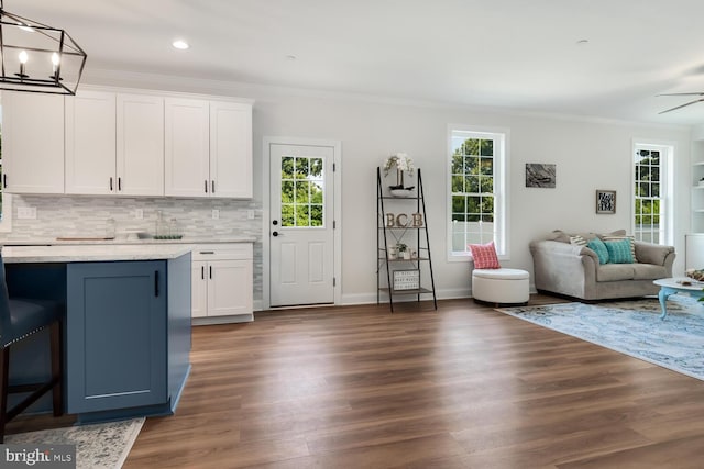 kitchen with ceiling fan with notable chandelier, decorative light fixtures, white cabinets, dark hardwood / wood-style flooring, and ornamental molding