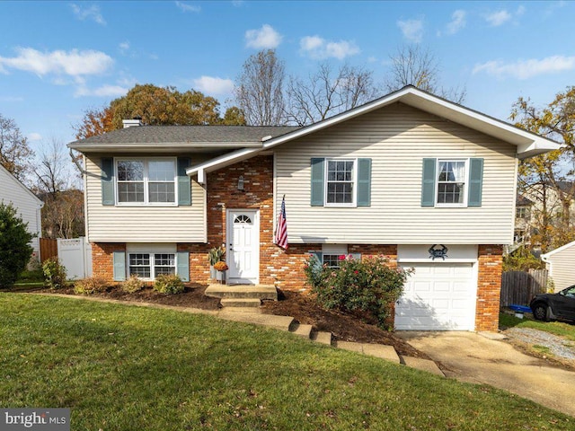 raised ranch featuring a garage and a front lawn