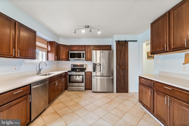 kitchen featuring a barn door, light tile patterned floors, sink, and appliances with stainless steel finishes