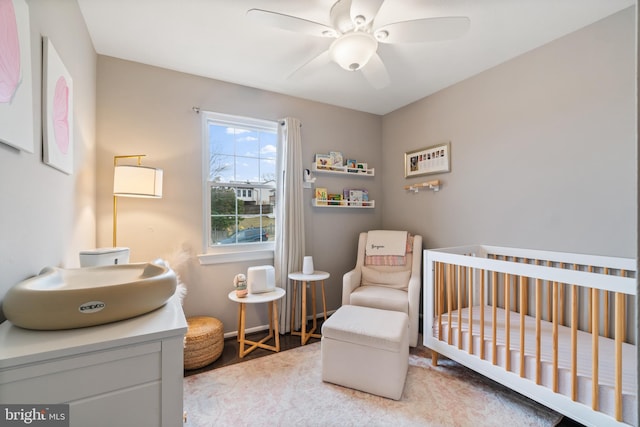 bedroom with ceiling fan and a crib