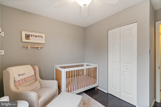 bedroom featuring ceiling fan, dark hardwood / wood-style floors, a crib, and a closet