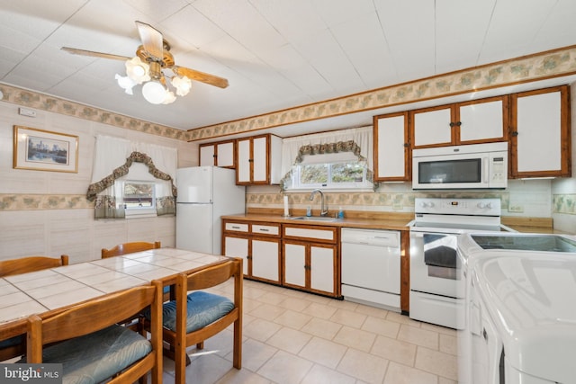 kitchen with decorative backsplash, white appliances, ceiling fan, sink, and white cabinetry