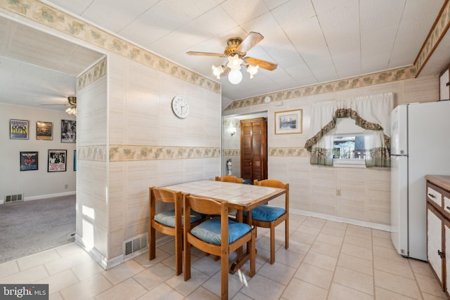 carpeted dining area with ceiling fan