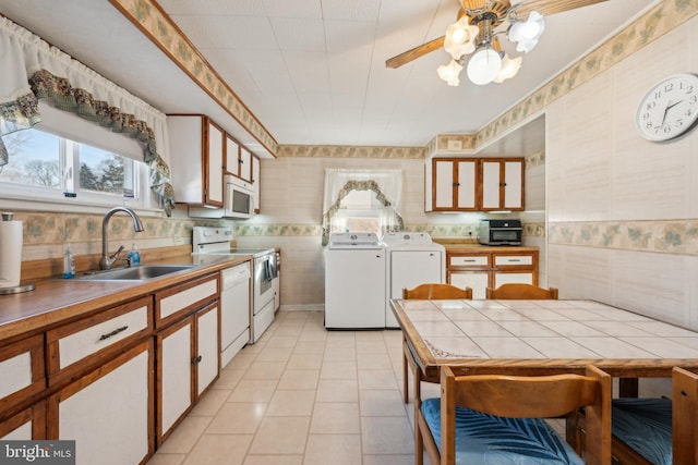 kitchen featuring washer and clothes dryer, white cabinets, white appliances, and sink