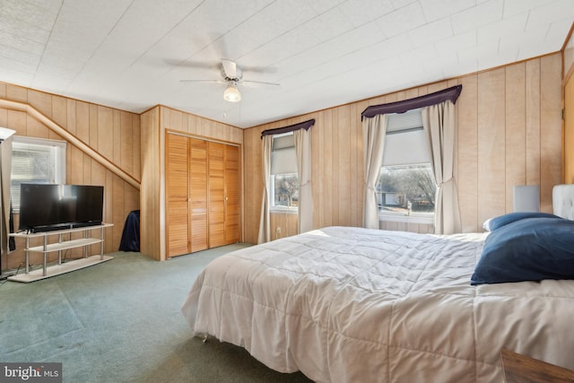 carpeted bedroom with a closet, ceiling fan, and wooden walls