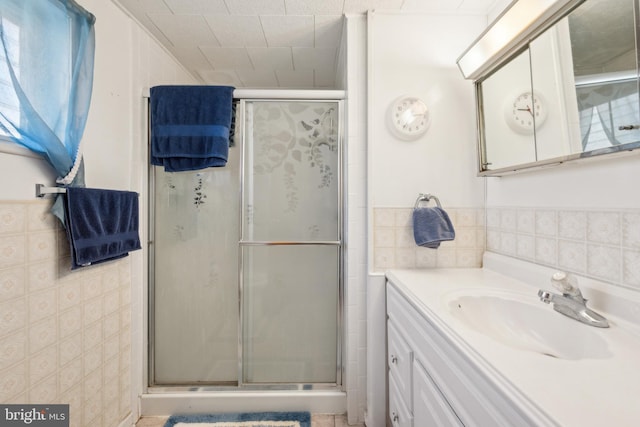 bathroom featuring an enclosed shower, vanity, and tile walls